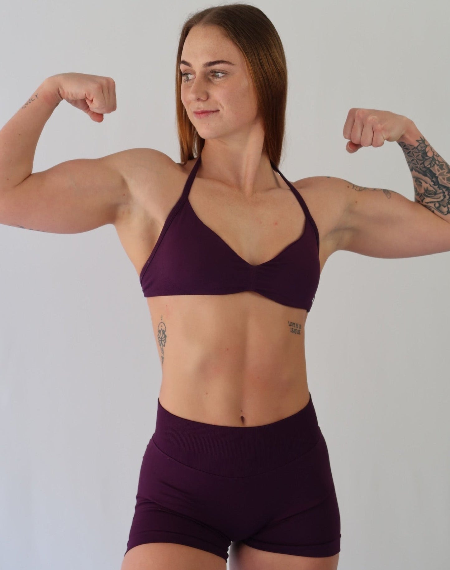 Model flexing her biceps in the deep grape set - front view