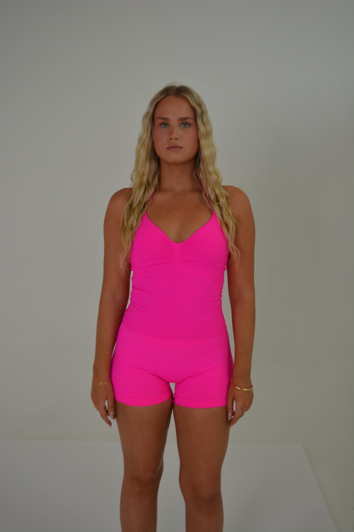 Girl standing in front of a white wall with a bright pink set on