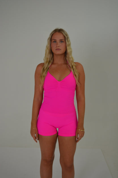 Girl standing in front of a white wall with a bright pink set on